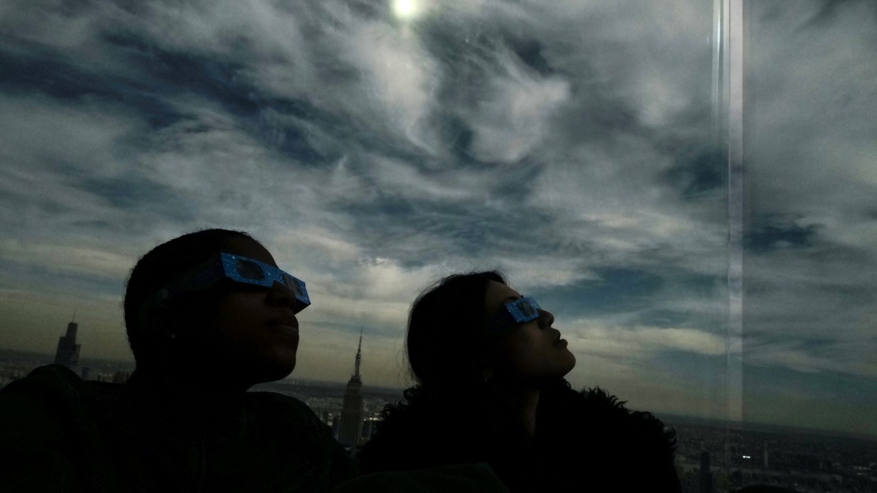 People look toward the sky at the 'Edge at Hudson Yards' observation deck during a total solar eclipse across North America, in New York City on April 8, 2024. This year's path of totality is 115 miles (185 kilometers) wide and home to nearly 32 million Americans, with an additional 150 million living less than 200 miles from the strip. The next total solar eclipse that can be seen from a large part of North America won't come around until 2044. (Photo by Charly TRIBALLEAU / AFP)
