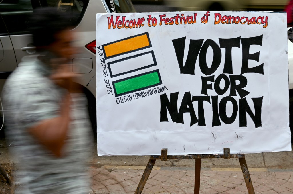 A pedestrian walks past an election themed painting placed by art students along a street outside their class to encourage people to vote in India's upcoming general elections, in Mumbai on April 17, 2024. (Photo by Indranil Mukherjee / AFP)