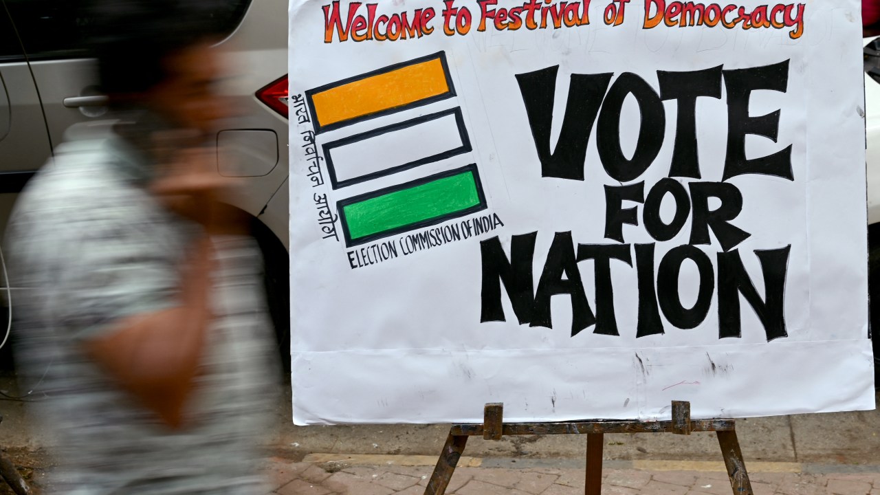 A pedestrian walks past an election themed painting placed by art students along a street outside their class to encourage people to vote in India's upcoming general elections, in Mumbai on April 17, 2024. (Photo by Indranil Mukherjee / AFP)