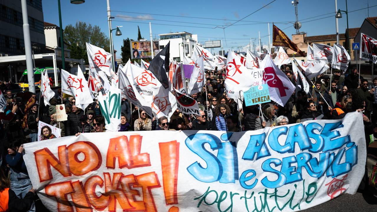 Manifestantes segurando um cartaz escrito "Não aos ingressos, sim às casas e serviços à todos" em protesto contra a cobrança da taxa para turistas em Veneza, Itália. 25/04/2024.