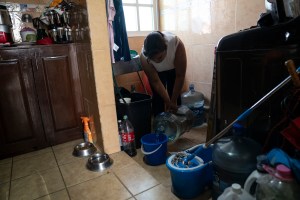 Moradora do bairro Las Peñas, na Cidade do México, armazena água durante racionamento