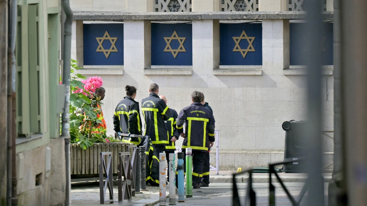 Fire brigade members stand by a synagogue in the Normandy city of Rouen where French police have killed earlier an armed man who was trying to set fire to the building on May 17, 2024. Two separate investigations have been opened, one into the fire at the synagogue and another into the circumstances of the death of the individual killed by the police, Rouen prosecutors said. The man threatened a police officer with a knife and the latter used his service weapon, he added. (Photo by LOU BENOIST / AFP)