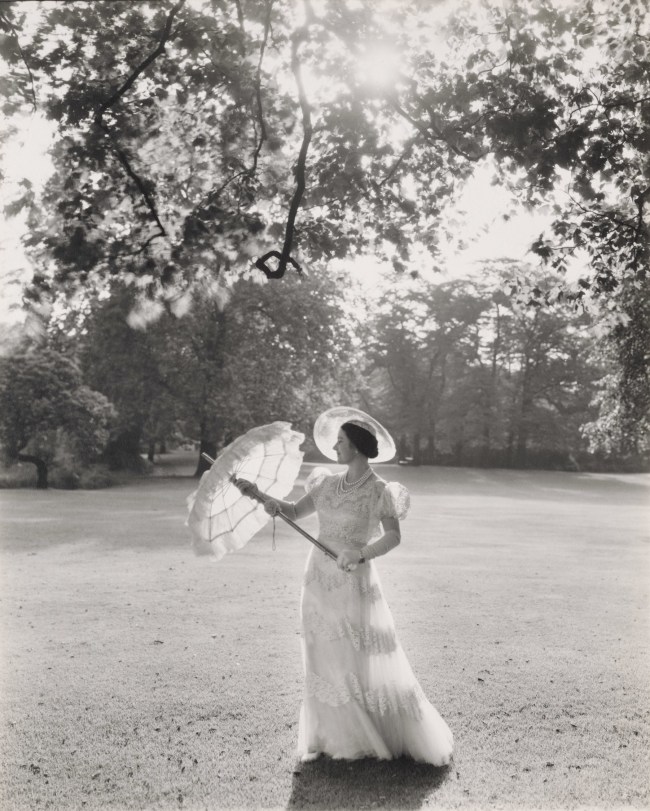 A Rainha Mãe, esposa de George V e mãe de Elizabeth II, é fotografada no Palácio de Buckingham em 1939. Ela usa um dos vestidos que Norman Hartnell desenhou para a Visita de Estado à França em 1938, conhecido como “Guarda-roupa Branco”, que se tornou uma sensação da moda. -
