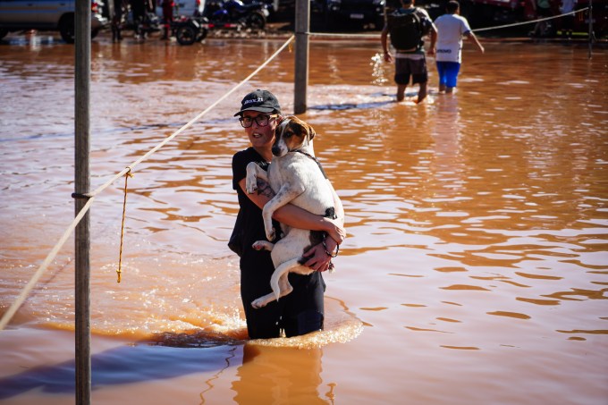 Um morador carrega um cachorro nas enchentes após fortes chuvas em Porto Alegre, Rio Grande do Sul, Brasil, na segunda-feira, 6 de maio de 2024