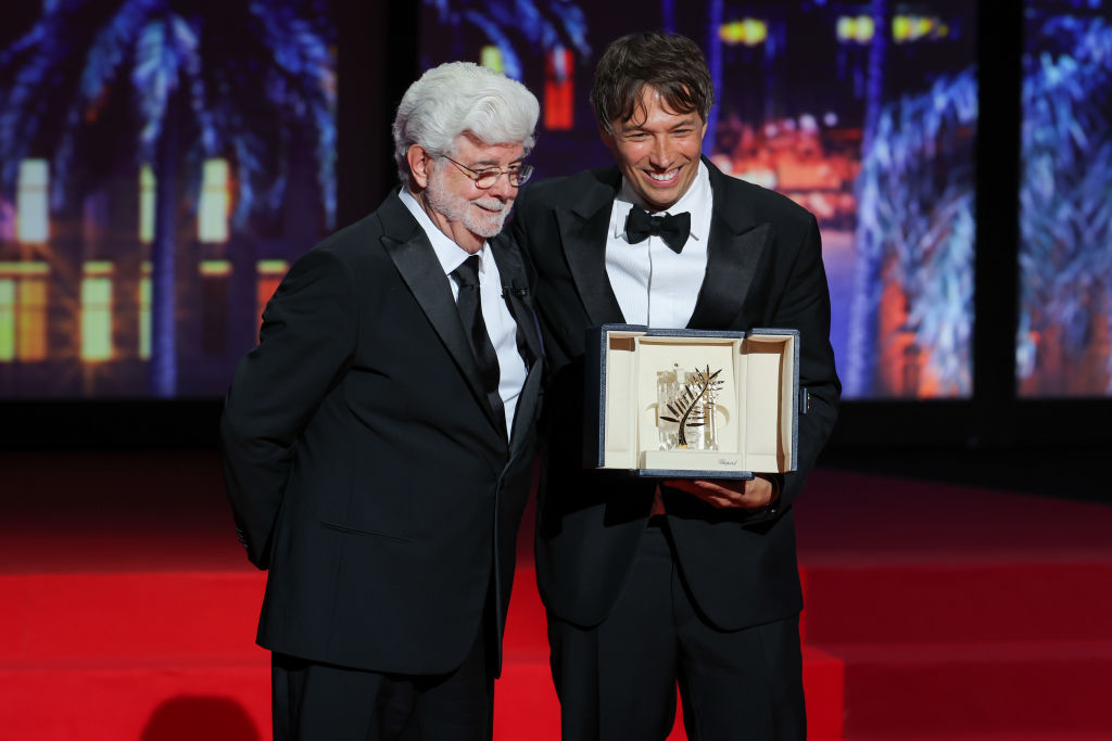 Sean Baker (à dir.) recebe a Palma de Ouro do diretor George Lucas no encerramento do Festival de Cannes 2024, na França