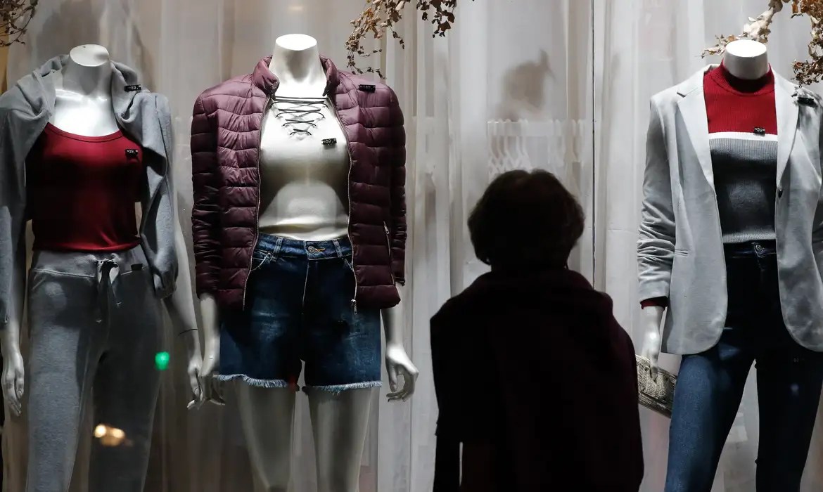 Mulher observa roupas em vitrina de loja