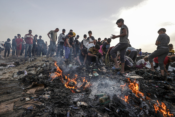 Palestinos observando os destroços do ataque aéreo israelense contra um acampamento para desabrigados na cidade de Rafah, no sul da Faixa de Gaza. 27/05/2024