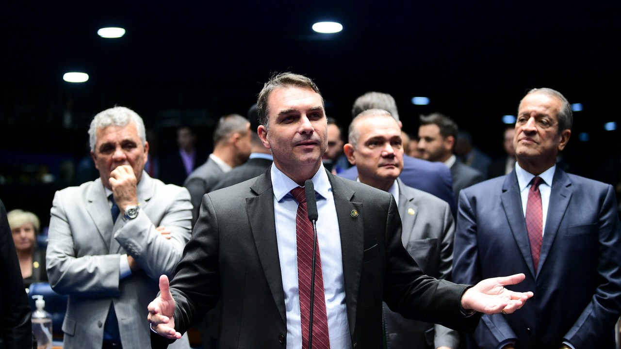 Flávio Bolsonaro discursa no Senado, observado pelo deputado Alberto Fraga e por Valdemar Costa Neto
