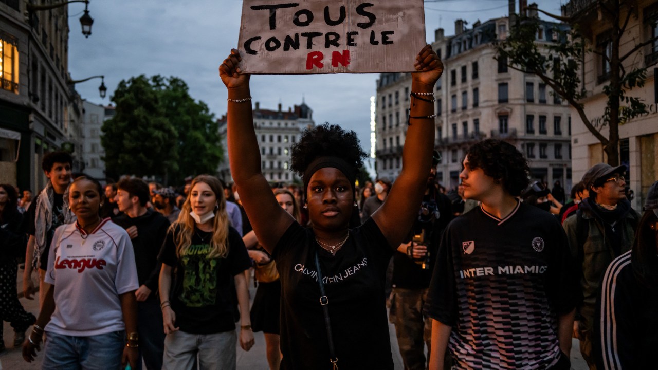 Manifestante segurando um cartaz escrito "Todos contra o RN" em protesto contra o avanço da extrema direita em Lyon, França. 30/06/2024