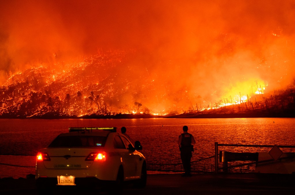 Law enforcement members watch as the Thompson fire burns over Lake Oroville in Oroville, California on July 2, 2024. A heatwave is sending temperatures soaring resulting in red flag fire warnings throughout the state. (Photo by JOSH EDELSON / AFP)
