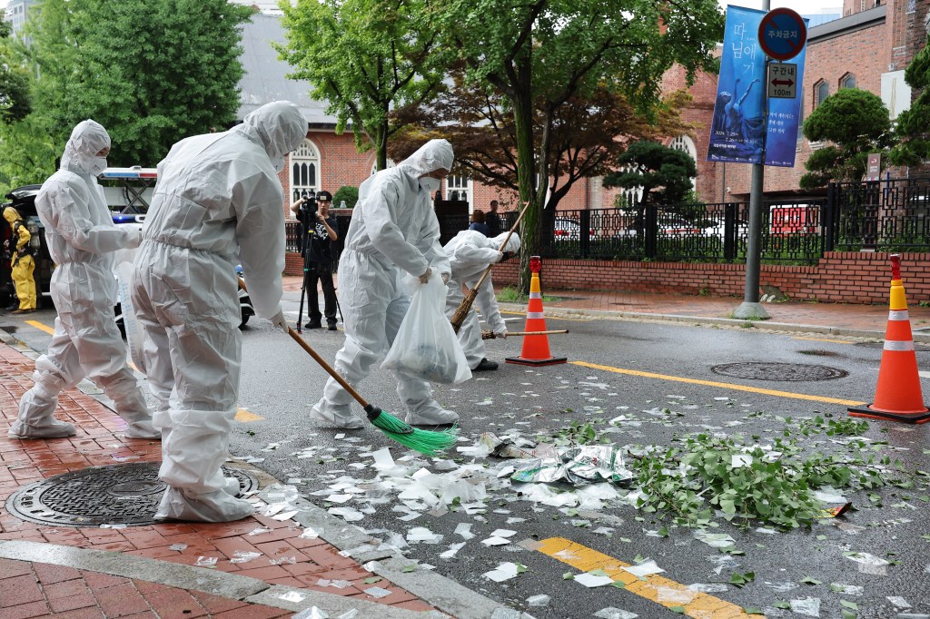 South Korean officials clean up the contents of a trash-carrying balloon sent by North Korea after it landed on a street in Seoul on July 24, 2024. This is the tenth time the North has sent the balloons across the border this year in what it claims is retaliation for anti-regime propaganda balloons launched by South Korean activists. (Photo by YONHAP / AFP) / - South Korea OUT / NO ARCHIVES - RESTRICTED TO SUBSCRIPTION USE