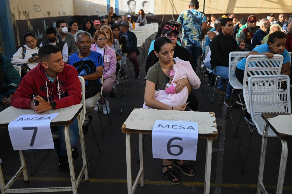 People wait for their turn to vote at a polling station in Caracas, during the Venezuelan presidential election on July 28, 2024. Venezuelans vote Sunday between continuity in President Nicolas Maduro or change in rival Edmundo Gonzalez Urrutia amid high tension following the incumbent's threat of a "bloodbath" if he loses, which polls suggest is likely. (Photo by Federico PARRA / AFP)