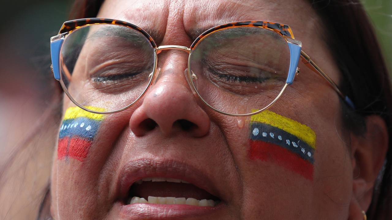 A woman cries outside the Venezuelan consulate in Medellin, Colombia, on July 28, 2024. Venezuelans vote Sunday between continuity in President Nicolas Maduro or change in rival Edmundo Gonzalez Urrutia amid high tension following the incumbent's threat of a "bloodbath" if he loses. (Photo by JAIME SALDARRIAGA / AFP)