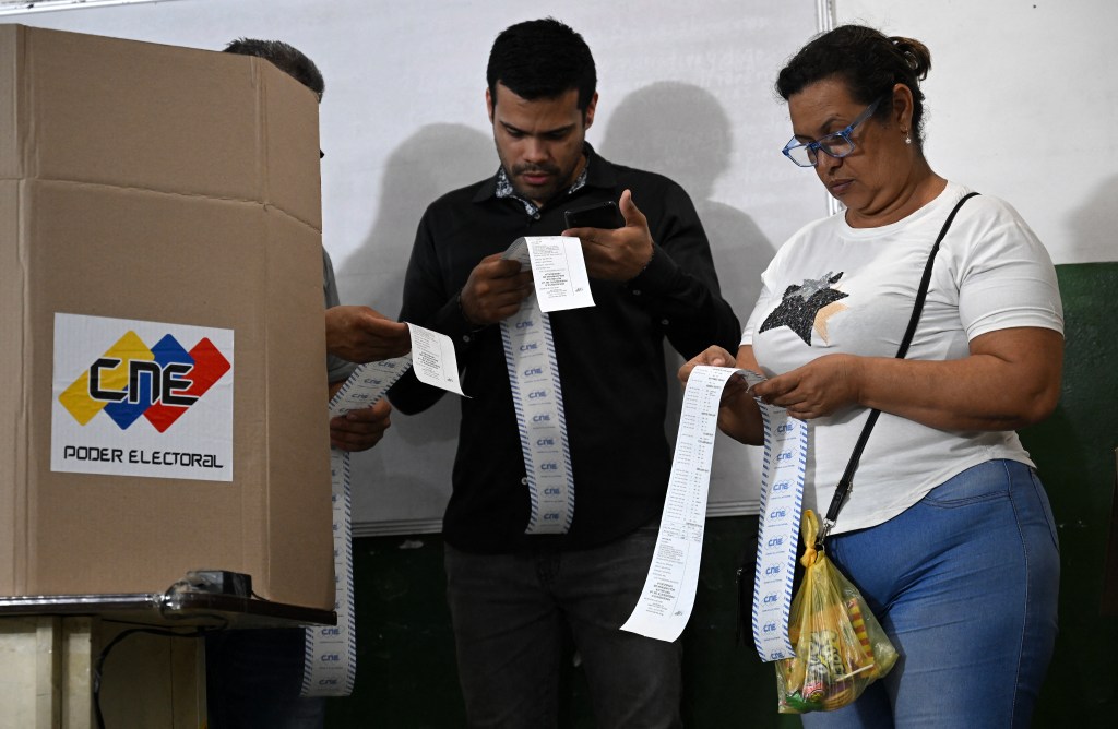 Election staffers count votes after polling stations closed during the presidential election, in Caracas on July 28, 2024. Venezuelans vote Sunday between continuity in President Nicolas Maduro or change in rival Edmundo Gonzalez Urrutia amid high tension following the incumbent's threat of a "bloodbath" if he loses, which polls suggest is likely. (Photo by Raul ARBOLEDA / AFP)