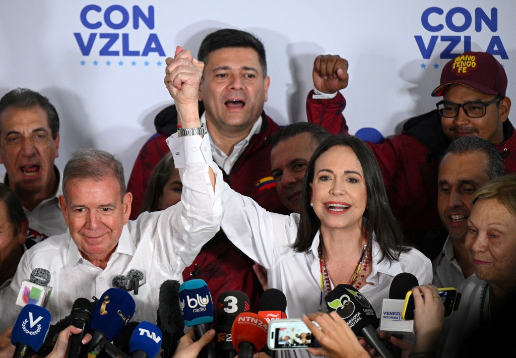 Venezuelan opposition leader Maria Corina Machado (R) speaks with the media next to opposition presidential candidate Edmundo Gonzalez Urrutia while waiting for the results of the presidential election, in Caracas on July 28, 2024. Venezuela's opposition leader Maria Corina Machado urged voters in the country's presidential election to remain at their polling stations to verify the counting process in the "decisive hours" after closing. (Photo by Federico PARRA / AFP)