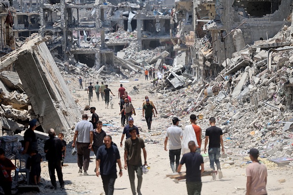 Palestinos caminhando pelos destroços de edifícios após ofensiva israelense na Cidade de Gaza. 11/07/2024