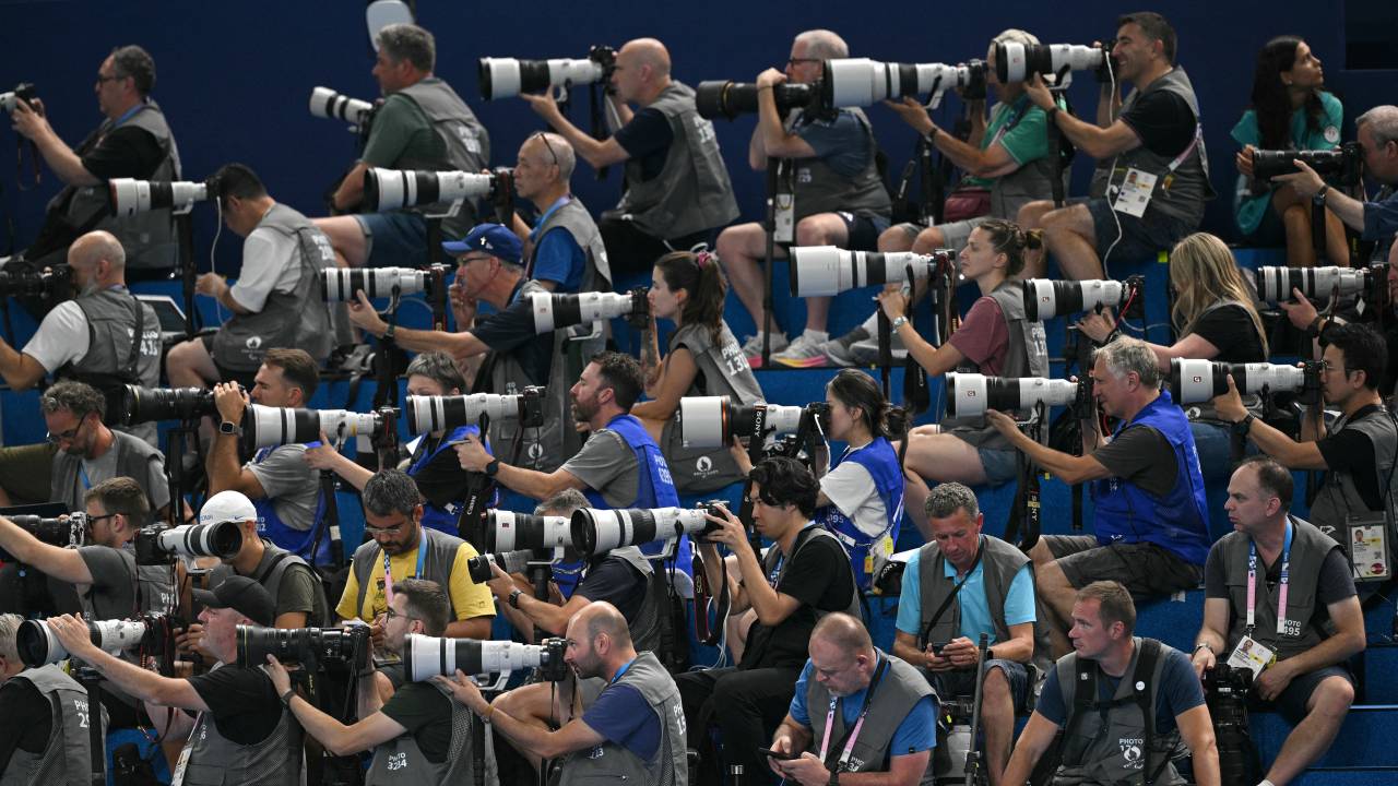Photographers work during the evening finals session of the swimming event during the Paris 2024 Olympic Games at the Paris La Defense Arena in Nanterre, west of Paris, on July 29, 2024. (Photo by Oli SCARFF / AFP)