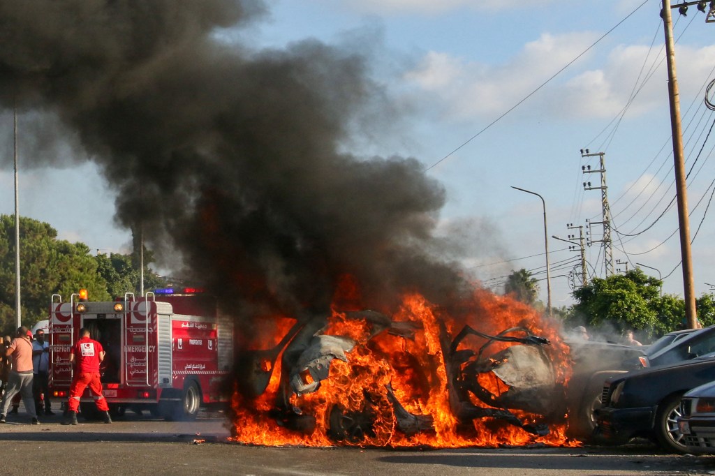 Firefighter arrive as a car burns following an Israeli strike in the southern Lebanese city of Sidon on August 9, 2024. A Lebanese security source said the Israeli strike on a vehicle in the southern city of Sidon killed a Hamas security official from the nearby Ain al-Helweh Palestinian refugee camp. (Photo by Mahmoud ZAYYAT / AFP)