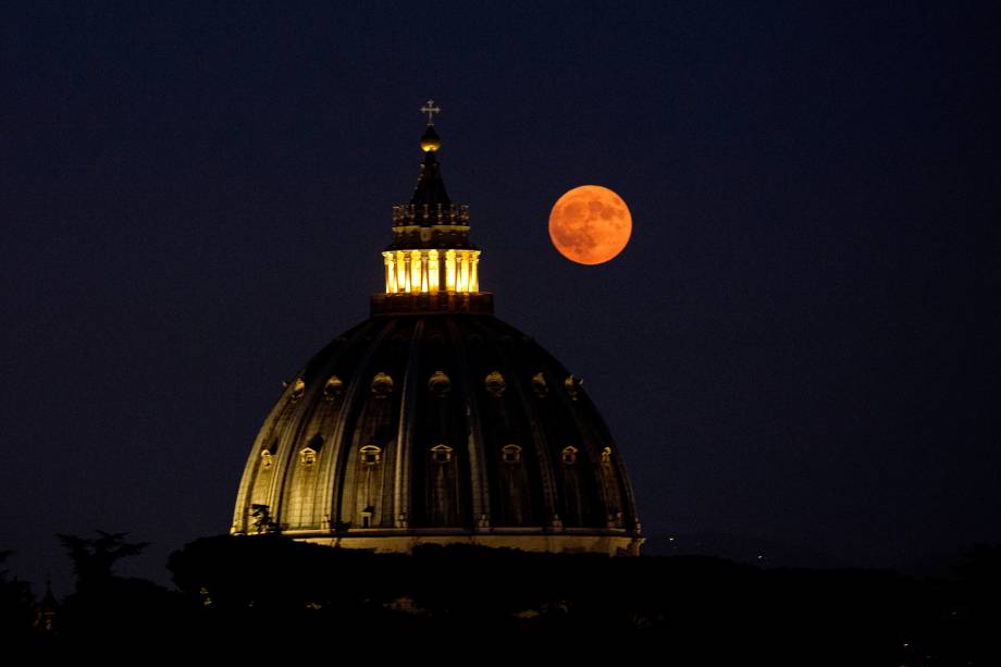 Esta fotografia tirada em Roma mostra a Super Lua Azul nascendo sobre a cúpula da Basílica de São Pedro, na Cidade do Vaticano, na itália