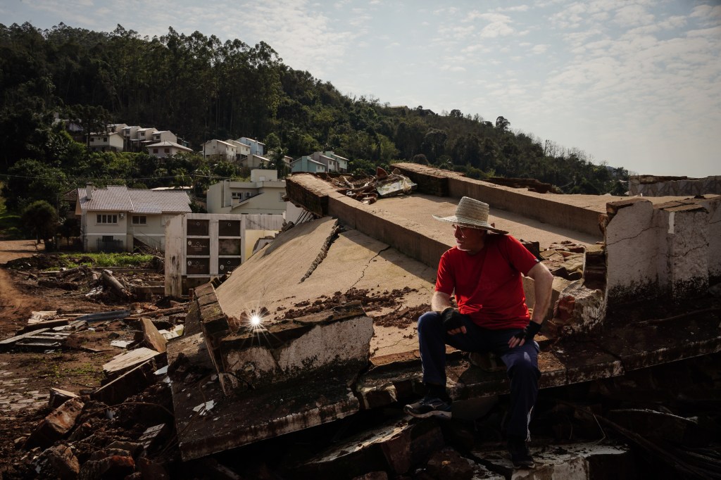 MUÇUM,RS, BRASIL - 01/08/2024 - Reportagem conta como está a reconstrução na pacata cidade no Vale do Taquari, que ficou conhecida depois que inúmeras enchentes, desde setembro de 2023, destruíram parte da cidade. Na foto, o morador Jairo Marobino sentado no que restou do Cemitério Municipal, levado pela correnteza do Rio Taquari. (FOTO: Carlos Macedo/Veja).