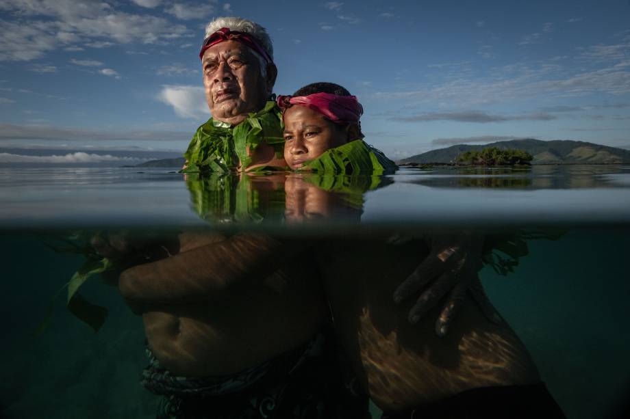 Kioan Climate Emergency Declaration meetings on Kioa Island, Fiji. Kioa island resident Lotomau Fiafia and his grandson John, Lotomau was born on the island in 1952, he saw the changes of the shore line in the past decades, picture of him standing in the water roughly where the shore line used to be when he was young, and now its up to his chest.8 August 2023. The Age News. Photo: Eddie Jim.