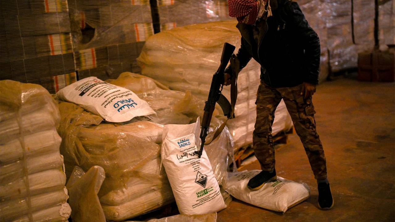 Syrian rebel fighters inspect sacks marked to contain "Saudi-made" flakes of caustic soda at a drug manufacturing facility in the city of Douma in the Eastern Ghouta region on the eastern outskirts of Damascus on December 12, 2024. The dramatic collapse of Bashar al-Assad's Syrian regime has thrown light into many of the dark corners of his rule, including the industrial-scale export of the banned drug Captagon. Victorious Islamist fighters have seized military bases and distribution hubs for the amphetamine-laced stimulant, which has flooded the black market across the Middle East. (Photo by Aris MESSINIS / AFP)
