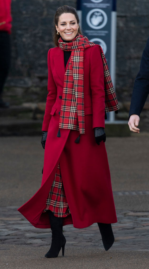 O casaco vermelho Alexander McQueen, a saia Emilia Wickstead e as botas pretas da Ralph Lauren fizeram sucesso em 2020. Tanto que Kate repetiu o look em 2024. s&oacute; que ao inv&eacute;s do cachecol xadrez daquele ano, preferiu um moderno la&ccedil;o preto na gola