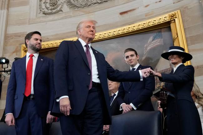 US-POLITICS-TRUMP-INAUGURATION O presidente Donald Trump, ao centro, segura a mão de sua esposa Melania Trump, à direita, enquanto seu filho Barron Trump, ao centro, e o vice-presidente JD Vance observam