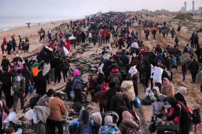 PALESTINIAN-ISRAEL-CONFLICT-DISPLACED People walk along Gaza's coastal al-Rashid Street in Nuseirat towards the Netzarim corridor to cross to the northern part of the Gaza Strip on January 27, 2025. Displaced Palestinians began returning to northern Gaza on January 27, an official at the territory's Hamas-run Interior Ministry told AFP, after a breakthrough in negotiations between Hamas and Israel. (Photo by BASHAR TALEB / AFP)