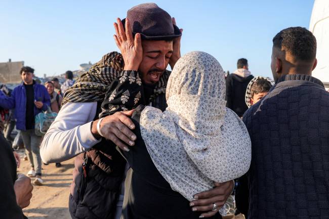 PALESTINIAN-ISRAEL-CONFLICT-DISPLACED A woman embraces a man after crossing the Netzarim corridor from the southern Gaza Strip north into Gaza City along Gaza's coastal al-Rashid Street on January 27, 2025. Displaced Palestinians began returning to northern Gaza on January 27, an official at the territory's Hamas-run Interior Ministry told AFP, after a breakthrough in negotiations between Hamas and Israel. (Photo by BASHAR TALEB / AFP)