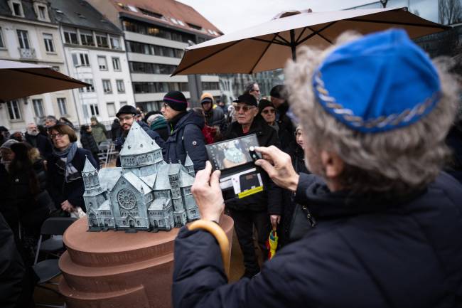 FRANCE-POLITICS-HISTORY-WWII-ANNIVERSARY A man takes a picture of a model of the local synagogue destroyed by the Nazis during the inauguration of the Memorial Gardens in Strasbourg, eastern France on January 27, 2025, as nations marked the 80th anniversary of the liberation of the Auschwitz extermination camp in Poland. (Photo by SEBASTIEN BOZON / AFP)