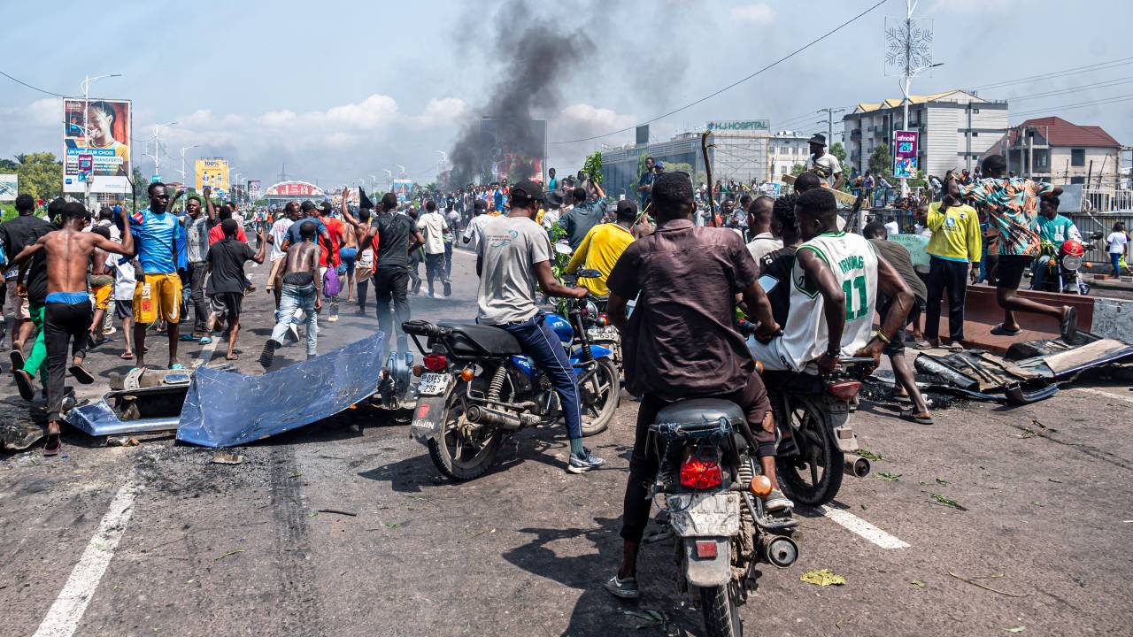Protesters gather as smoke billows from burning tires during a demonstration against the escalating conflict in eastern Democratic Republic of Congo in Kinshasa, on January 28, 2025. Protesters have attacked several embassies in DR Congo's capital Kinshasa, including that of Rwanda, during demonstrations on January 28,2025 against the escalating conflict in the country's east, diplomatic sources said. (Photo by Hardy BOPE / AFP)