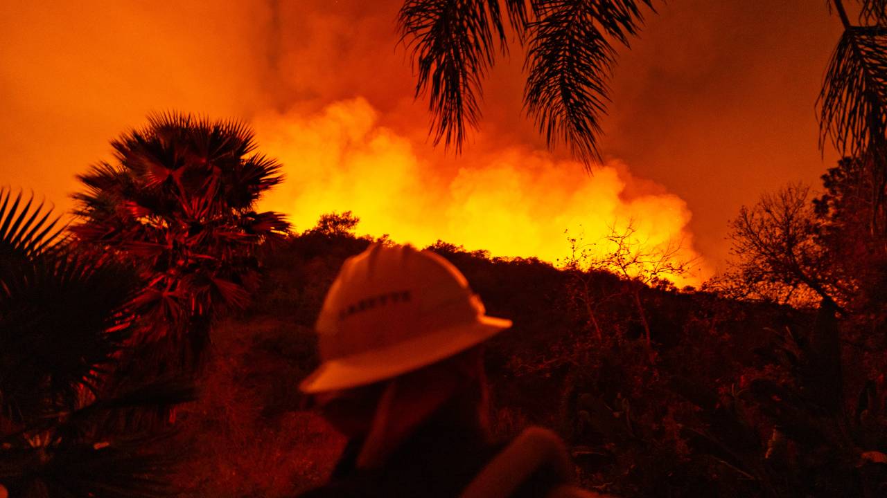 Bombeiro tenta controlar incêndio em uma estrada para Encino, na Califórnia, na madrugada de sábado (11/01/2025)