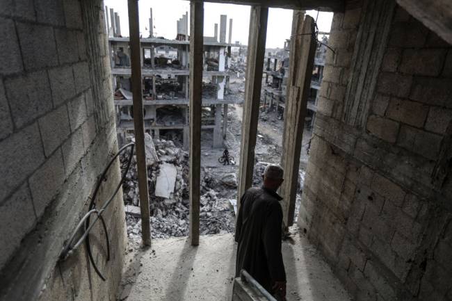 Palestinians continue to return to their homes as ceasefire comes into force in Gaza DEIR AL BALAH, GAZA - JANUARY 20: A man looks from inside a damaged building at the heavily damaged and partially collapsed buildings as displaced Palestinians continue to return their houses after the ceasefire and hostage-prisoner swap deal between Hamas and Israel at Bureij refugee camp in Deir al-Balah, Gaza on January 20, 2025. (Photo by Ali Jadallah/Anadolu via Getty Images)