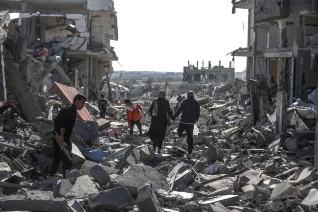 DEIR AL BALAH, GAZA - JANUARY 20: Displaced Palestinians continue to return their houses past heavily damaged and partially collapsed buildings after the ceasefire and hostage-prisoner swap deal between Hamas and Israel at Bureij refugee camp in Deir al-Balah, Gaza on January 20, 2025. (Photo by Ali Jadallah/Anadolu via Getty Images)