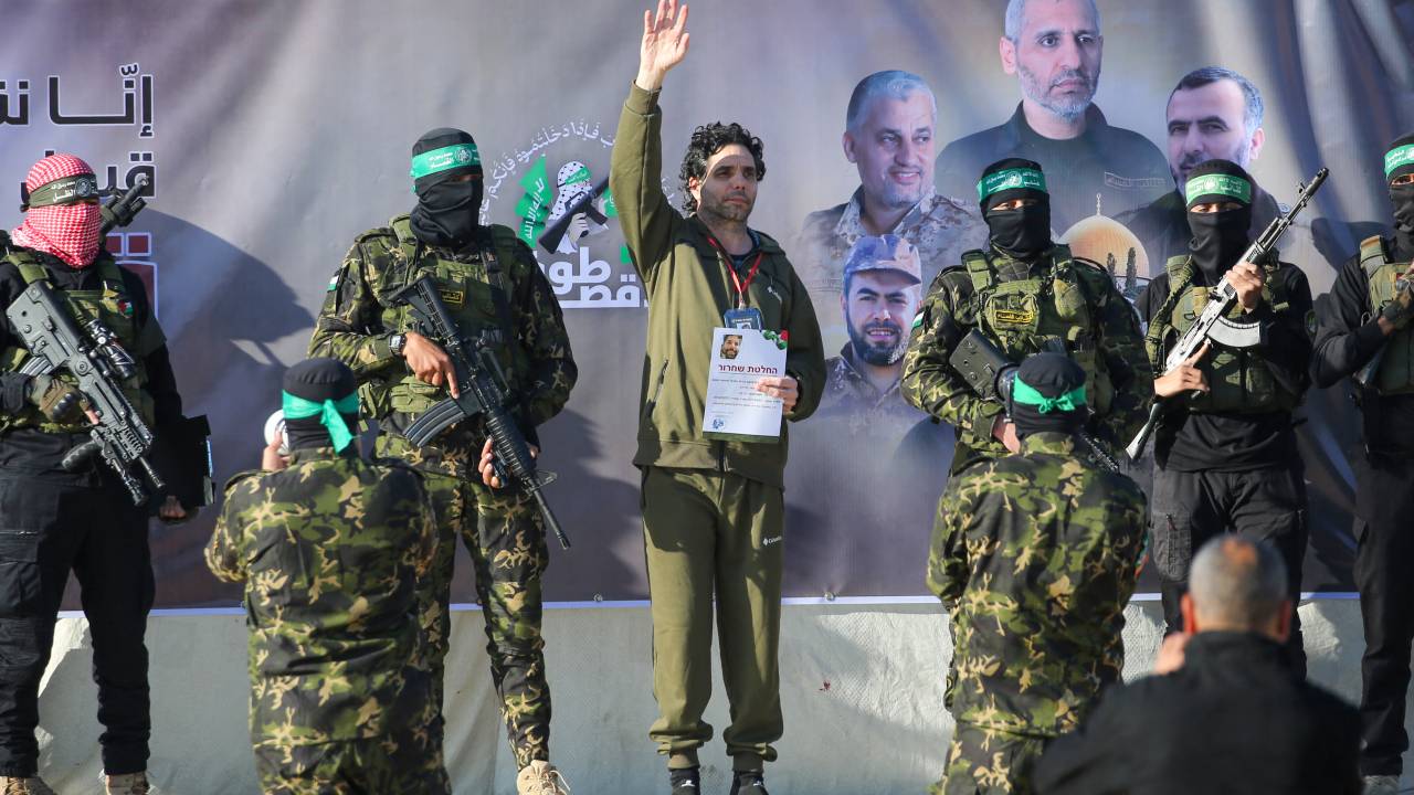 Palestinian militant group Hamas fighters escort Israeli-French hostage Ofer Kalderon on a stage before handing him over to a Red Cross team in Khan Yunis on February 1, 2025, as part of fourth hostage-prisoner exchange. (Photo by Eyad BABA / AFP)