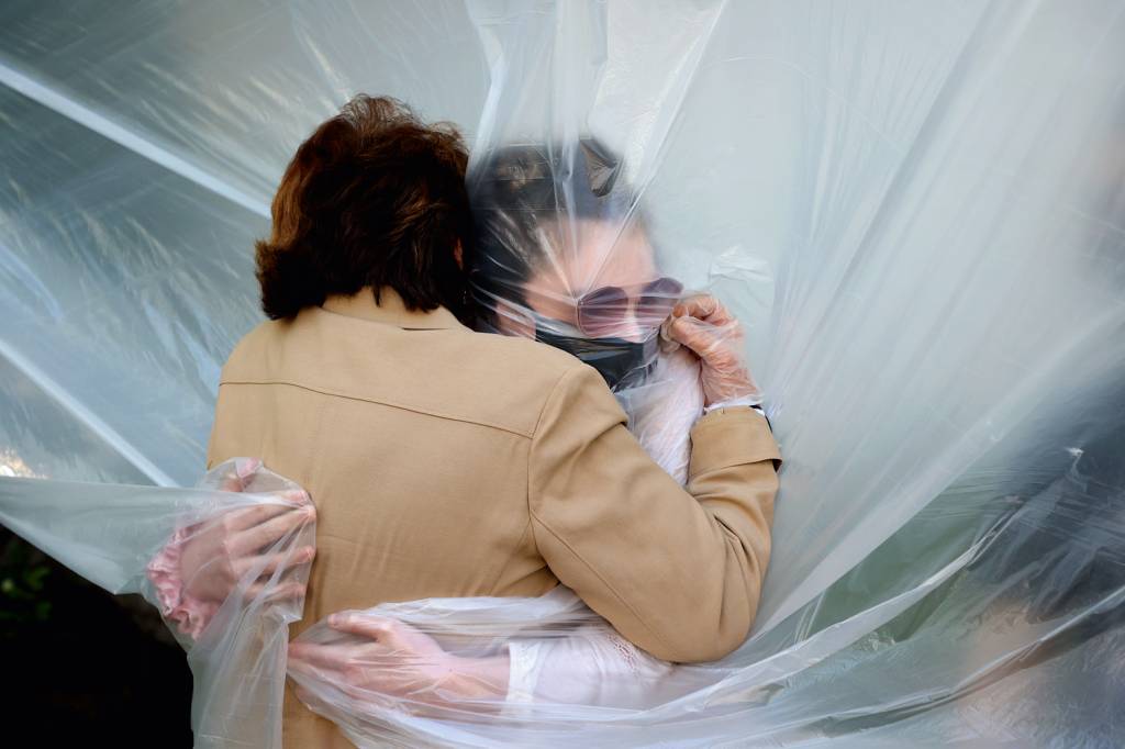 GettyImages-1226823033.jpg SAUDADE - Criatividade: diante da insegurança do contato, até abraço com plástico buscou driblar a disseminação viral
