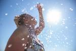 A young woman cools down with cold water during the summer heat.