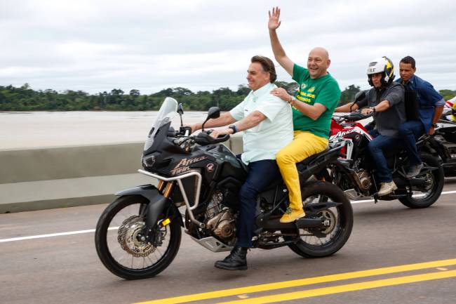 O então presidente Jair Bolsonaro e o empresário Luciano Hang, ambos sem capacete, andam de moto em ponte sobre o rio Madeira, na BR-364, em Rondônia, no dia 7 de maio de 2021 O então presidente Jair Bolsonaro e o empresário Luciano Hang, ambos sem capacete, andam de moto em ponte sobre o rio Madeira, na BR-364, em Rondônia, no dia 7 de maio de 2021