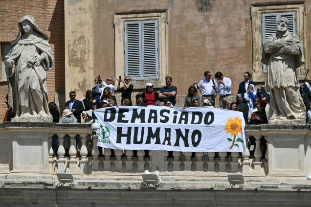 Pessoas seguram uma faixa com os dizeres 'Demasiado humano' enquanto participam da cerimônia fúnebre do falecido Papa Francisco. 26/04/2025 - Pessoas seguram uma faixa com os dizeres 'Demasiado humano' enquanto participam da cerimônia fúnebre do falecido Papa Francisco. 26/04/2025 -
