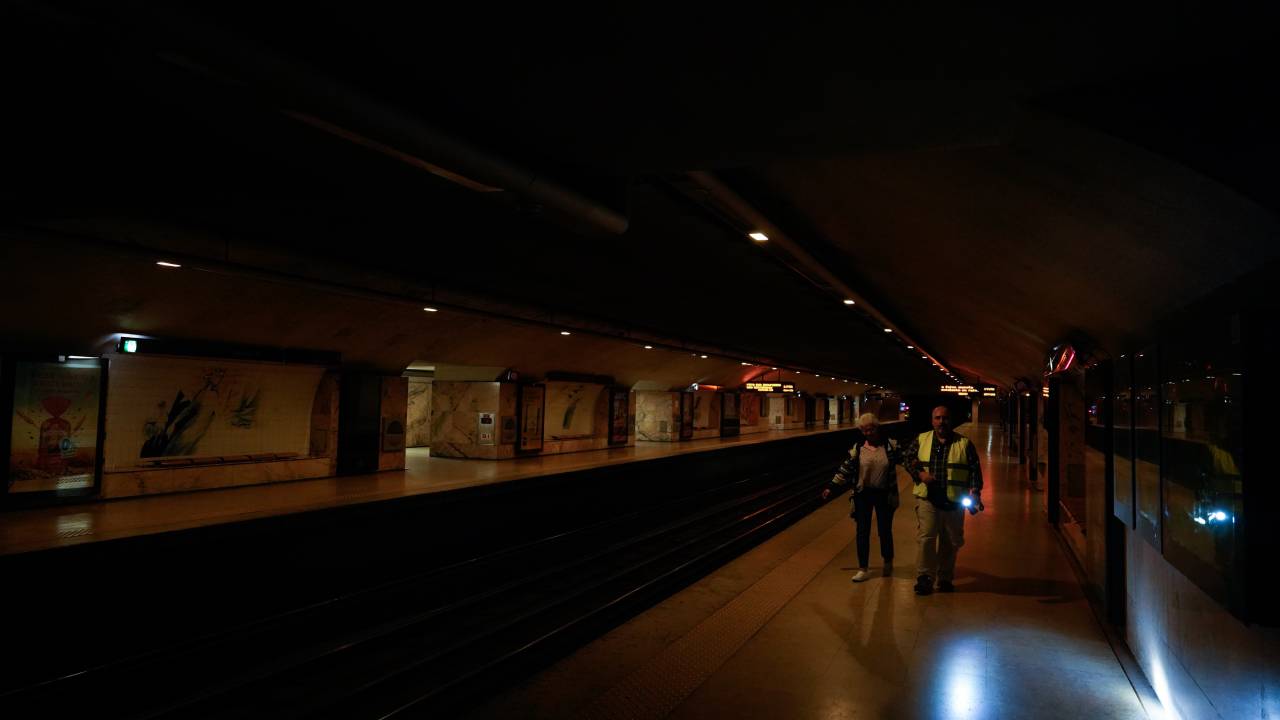 Um homem com uma lanterna lidera o caminho enquanto uma estação de metrô fica no escuro durante uma queda de energia em Lisboa, Portugal. 28/04/2025