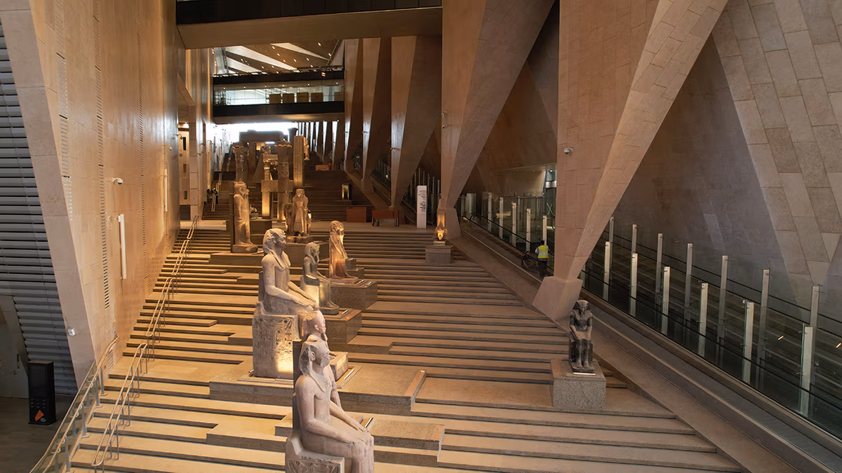 egito museu estátuas Escadaria monumental do Grand Egyptian Museum, ladeada por estátuas de faraós e deuses do antigo Egito, leva ao mirante com vista para as pirâmides.