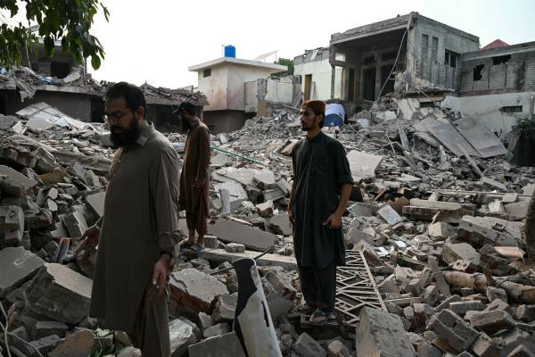 Locals stand on the debris of destroyed structures at the Government Health and Educational complex in Muridke about 30 kilometres from Lahore, on May 7, 2025, after Indian strikes. The death toll from Indian strikes on Pakistan has increased to eight, the country's military spokesman said on May 7, as India fired missiles at Pakistani territory and Islamabad vowed to "settle the score". (Photo by FAROOQ NAEEM / AFP)