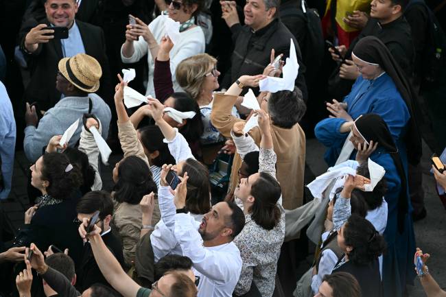VATICAN-RELIGION-POPE-CONCLAVE People react as white smoke (unseen) signals that cardinals elected a new pope during their conclave in the Vatican on May 8, 2025. (Photo by Gabriel BOUYS / AFP)