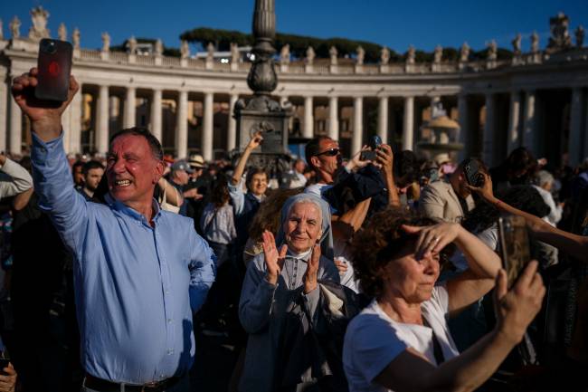 ITALY-VATICAN-RELIGION-POPE-CONCLAVE A nun (C) reacts as white smoke (unseen) signals that cardinals elected a new pope during their conclave in the Vatican on May 8, 2025. Thick black smoke billowed on May 8, 2025, from the chimney of the Sistine Chapel in a sign that cardinals again failed to elect a new head of the Catholic Church. (Photo by Dimitar DILKOFF / AFP)