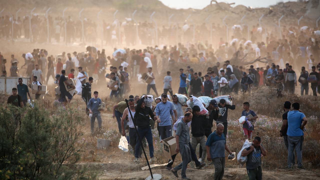 People carry relief supplies from the Gaza Humanitarian Foundation (GHF), a private US-backed aid group that has bypassed the longstanding UN-led system in the territory, as displaced Palestinians return from an aid distribution centre in the central Gaza Strip on June 8, 2025. The UN and major aid organisations have refused to cooperate with the GHF, citing concerns that it was designed to cater to Israeli military objectives. (Photo by Eyad BABA / AFP)