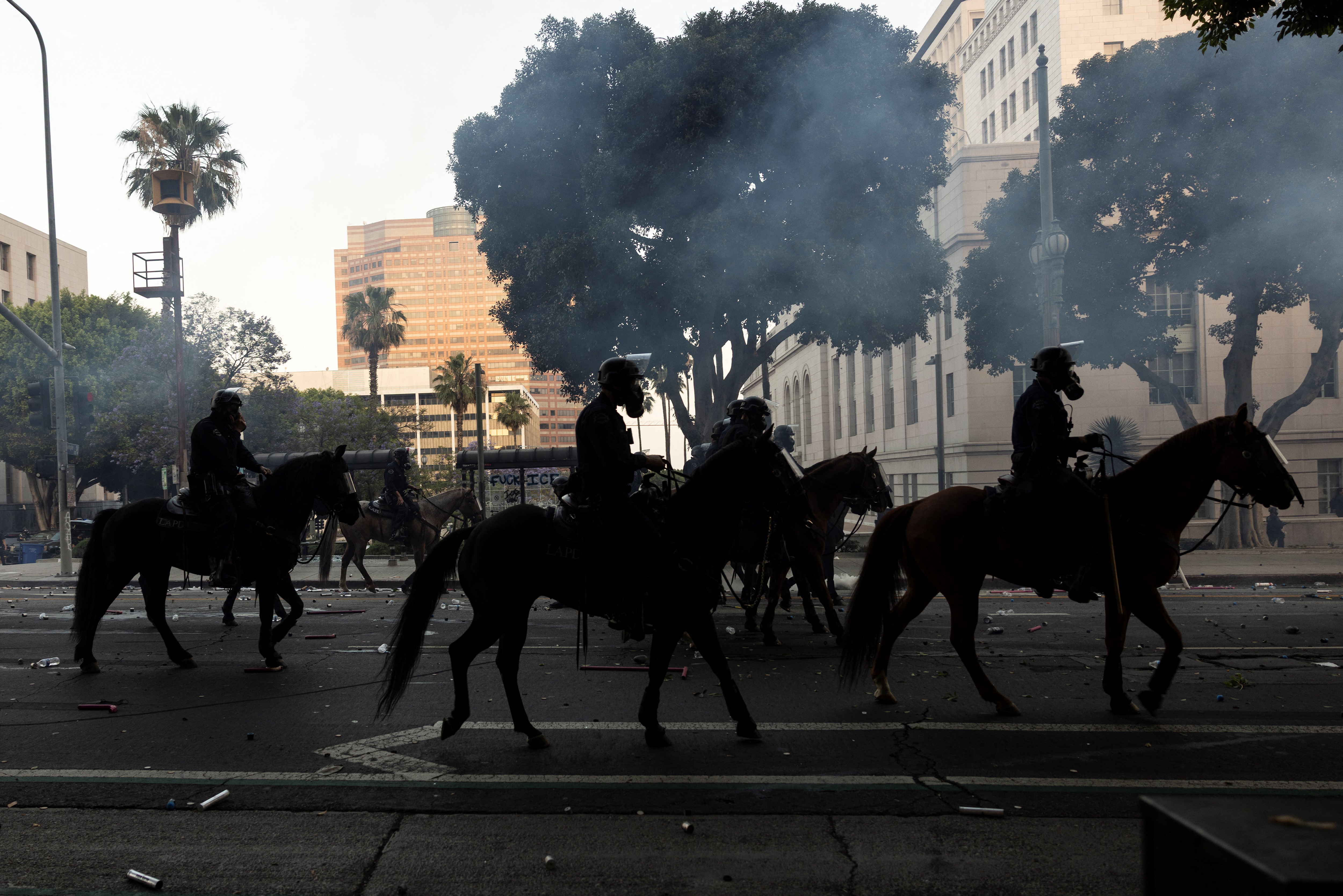 Los Angeles mounted police advance on a makeshift barricade in a cloud of tear gas as clashes erupt with demonstrators next to City Hall during a protest following federal immigration operations, in Los Angeles, California on June 8, 2025. Demonstrators torched cars and scuffled with security forces in Los Angeles on June 8, as police kept protestors away from the National Guard troops President Donald Trump sent to the streets of the second biggest US city. (Photo by ETIENNE LAURENT / AFP)