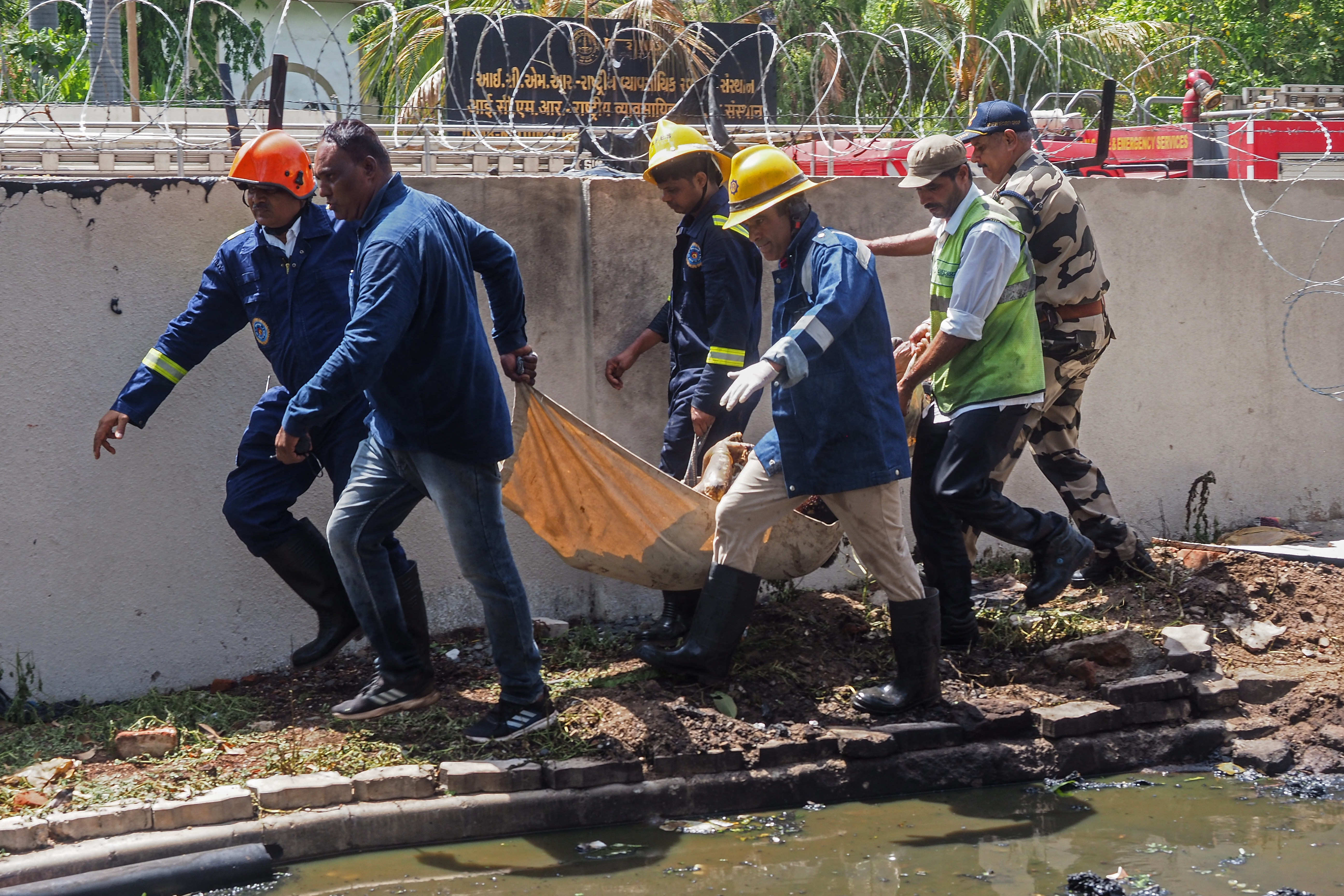 Firefighters carry a victim's body after the Air India flight 171 crashed in a residential area near the airport in Ahmedabad on June 12, 2025. The London-bound passenger plane crashed on June 12 in India's western city of Ahmedabad with 242 on board, aviation officials said in what the airline called a