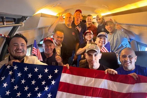 Dahud Hamid Ortiz em foto divulgada pelo Departamento de Estado. Ele está atrás da primeira fileira, com um boné cinza e próximo a uma bandeira americana pequena.