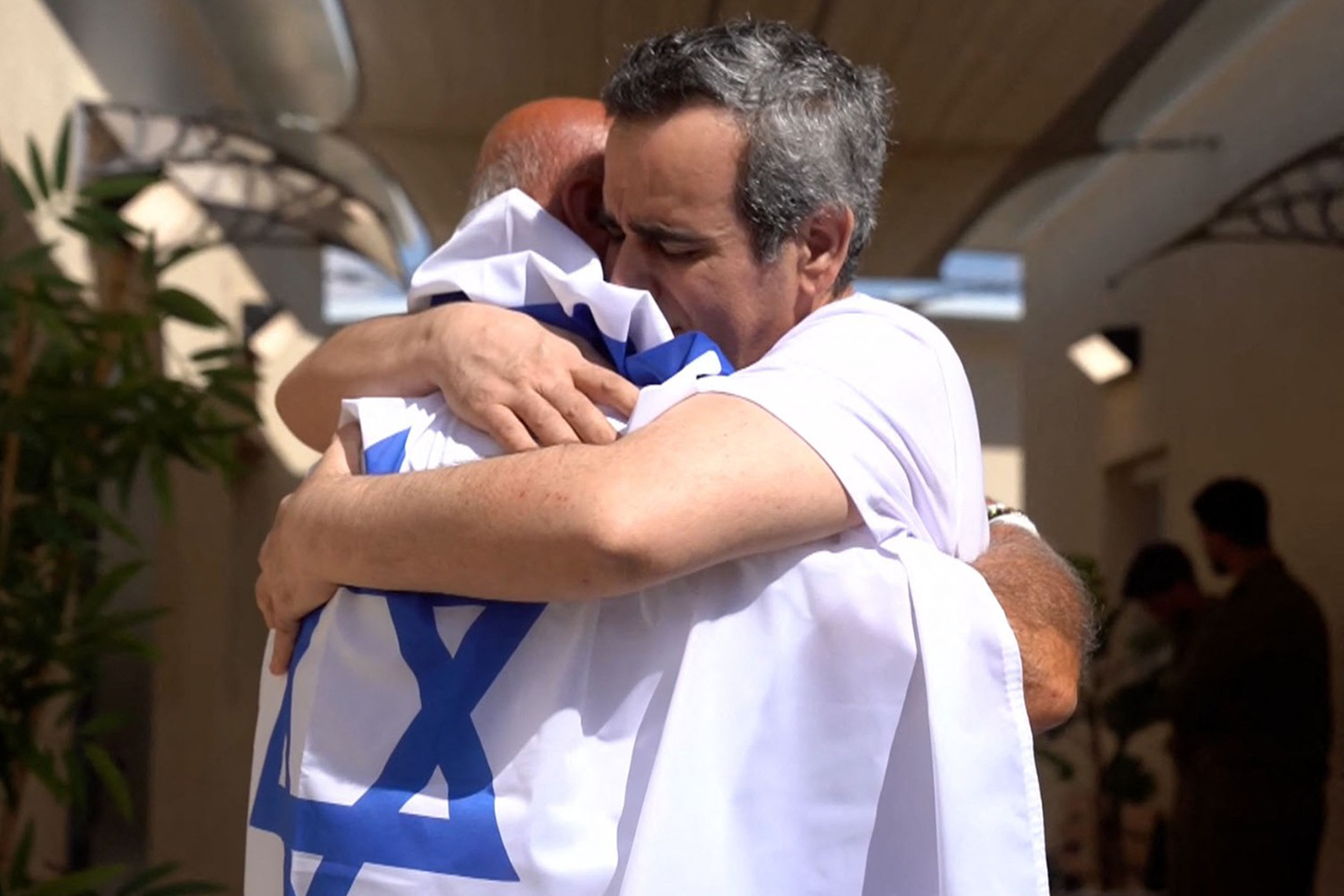 This handout picture released by the Israeli army shows released Israeli hostage Omri Miran (R), one of the former captives in Gaza since the 2023 October 7 attacks by Palestinian militants, being received by a family member after being handed over in a prisoner-hostage swap and a ceasefire deal between Israel and Hamas in Israel on October 13, 2025. (Photo by Israeli Army / AFP) / === RESTRICTED TO EDITORIAL USE - MANDATORY CREDIT